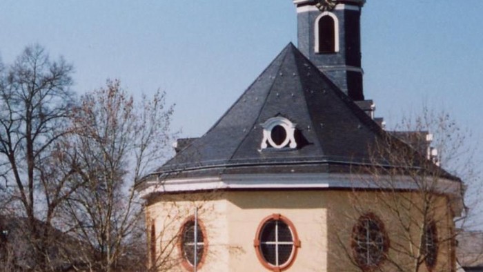 Ein gelbes Gebäude mit schwarzem Dach und Turm.