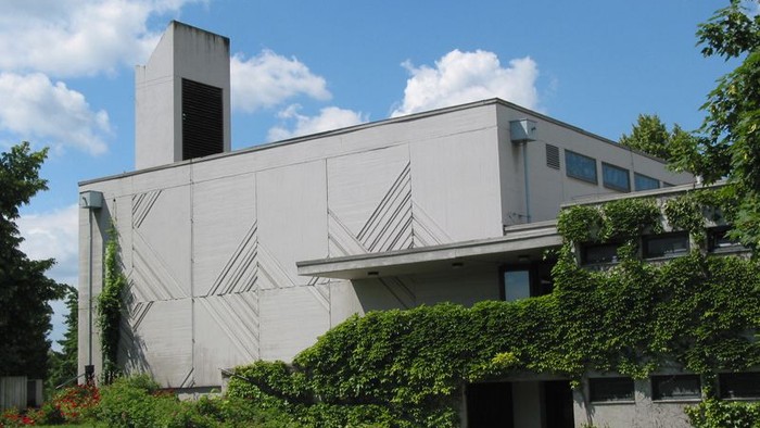 Modernes Gebäude mit flachem Dach und grünem Rasen davor