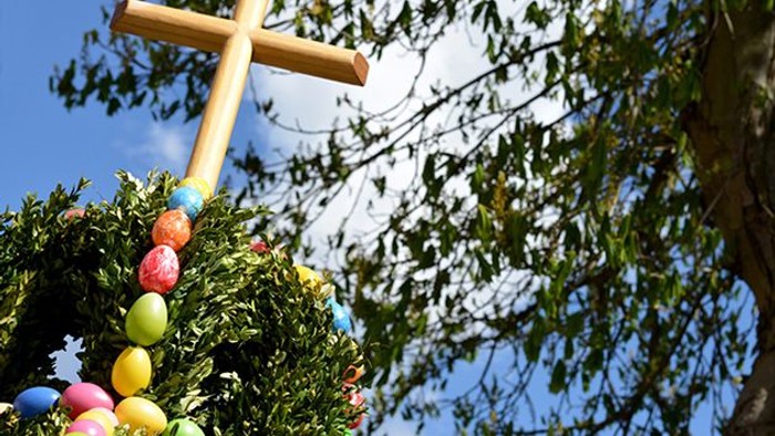 Ein bunter Osterkranz mit Kreuz an einem Baum