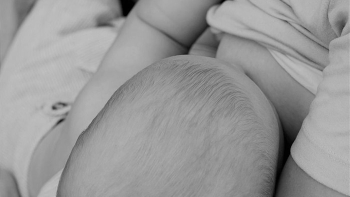Ein Baby wird von einer Person im Arm gehalten und schläft.