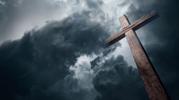 Ein hölzernes Kreuz vor dunklen Wolken