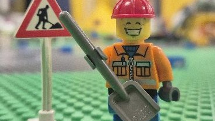 Ein Lego-Bauarbeiter steht neben einem Warnschild.