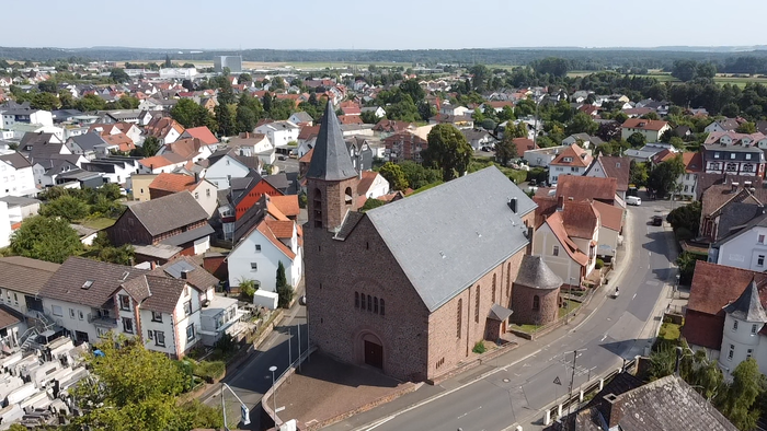 Ein Luftbild einer kleinen Stadt mit einem zentralen Kirchengebäude und umgebenden Häusern.