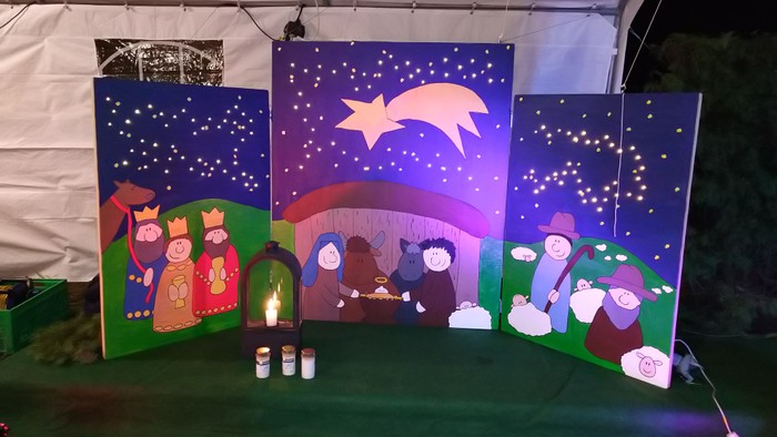 Ein Weihnachtskrippenbild mit Figuren und Kerzen in einer Kirche