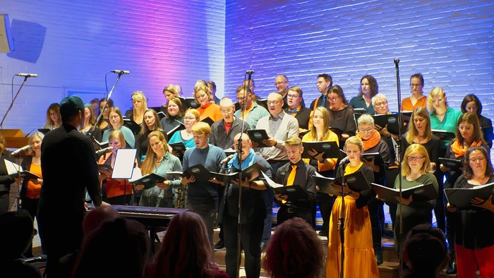 Ein Chor singt auf einer Bühne unter blauer Beleuchtung