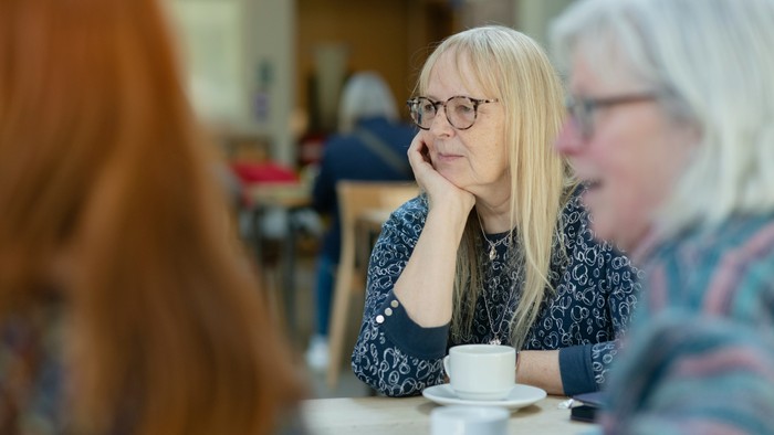 Zwei ältere Frauen sitzen in einem Café und unterhalten sich.