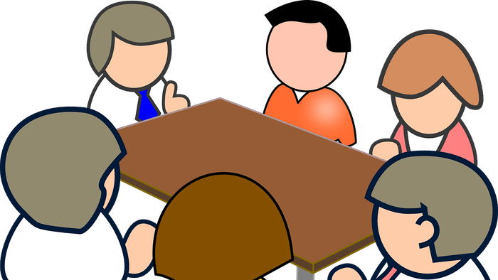 En gruppe af mennesker sidder om et bord og diskuterer.