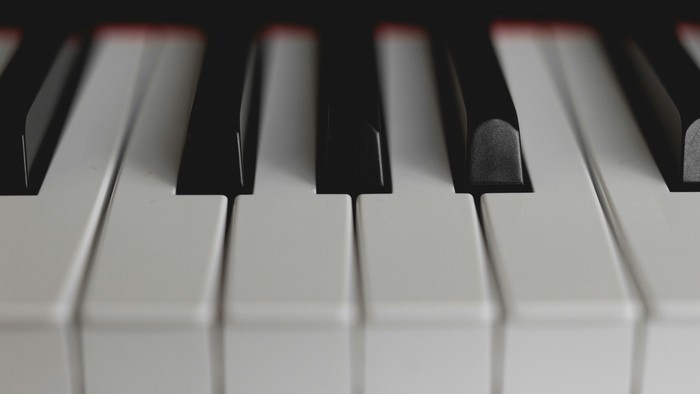 Nærbillede af et klaviatur med sorte og hvide tangenter i skarp kontrast mod en mørk baggrund.