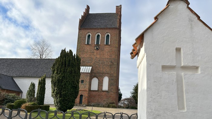 En kirke med tårn og en hvid kryds i forgrunden