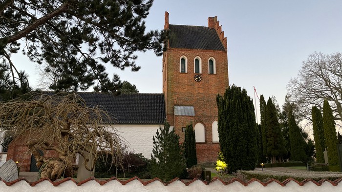 En kirke med tårn og mursten, omgivet af sne og træer