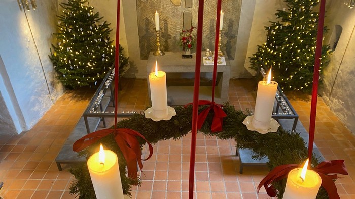 Julekrans med stearinlys og sløjfer i et flisebelagt rum med juletræer