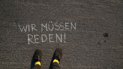Person steht vor der Aufschrift "Wir müssen reden!"