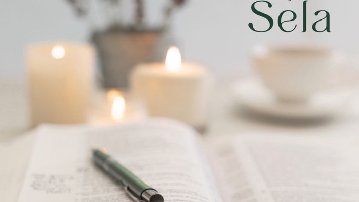 Ein offenes Buch mit Stift, Kerzen und Tee auf einem Tisch