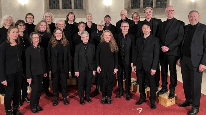 Ein Chor steht in einer Kirche auf einem roten Teppich.