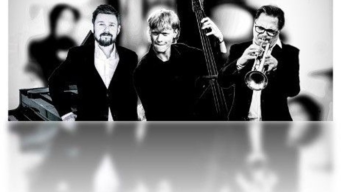 En trio af musikere spiller instrumenter på en scene