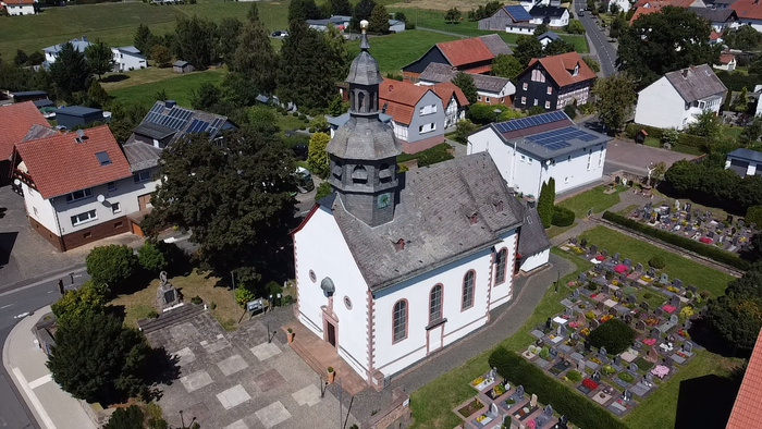 Überblick einer Kirche mit umliegendem Friedhof und Häusern