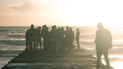 Eine Gruppe von Menschen steht am Strand bei Sonnenuntergang.
