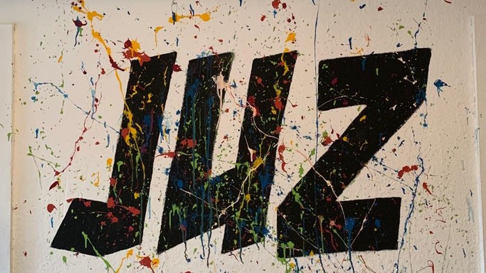 Schwarze Buchstaben „JWZ“ auf buntem, spritzigem Hintergrund