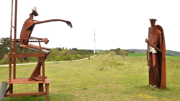 Zwei Metallskulpturen stehen in einem grasbewachsenen Feld.
