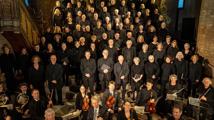 Ein großer Chor und Orchester posieren in einer Kirche