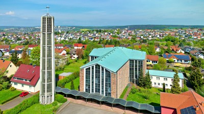 Ein moderner Gebäudekomplex mit hohem Turm und umliegender Wohnsiedlung