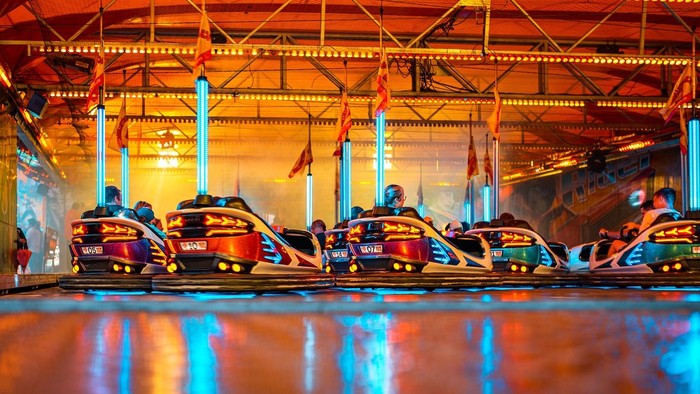 Ein Vergnügungspark mit bunten Autos auf einer Achterbahn, beleuchtet von bunten Lichtern.