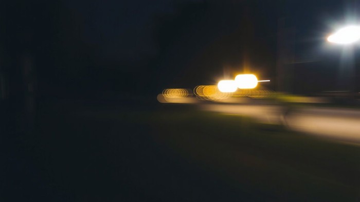 Dunkelheit mit hellen Lichtstreifen, möglicherweise von Autos oder Laternen.