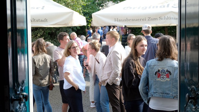 Menschen stehen vor einem Zelt und unterhalten sich