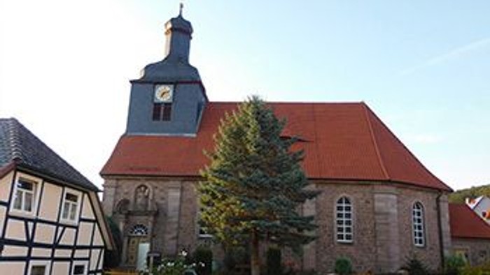 Das Bild zeigt eine Kirche mit einem Uhrturm und einem roten Dach.