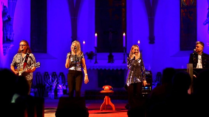 Eine Band spielt auf einer Bühne vor einem Publikum.