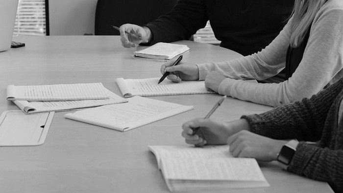 To studerende sidder ved bord og skriver i noter.