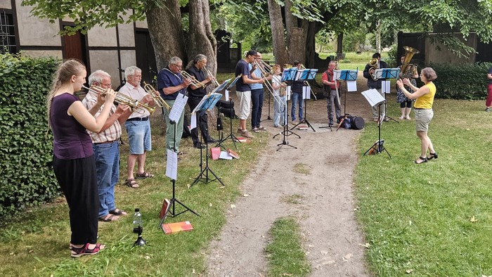 Eine Gruppe von Menschen singt im Freien unter Bäumen
