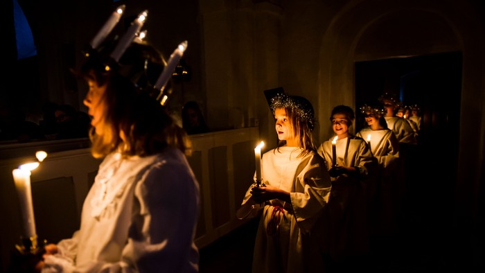 En gruppe børn i festlige kredenceremonier med lysekeruber og lysstaker