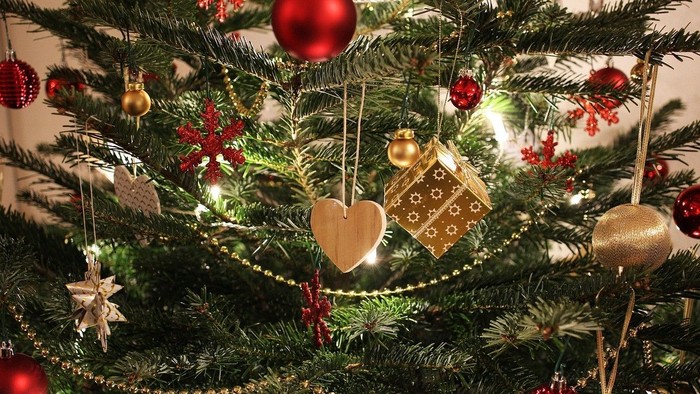 En juletree med røde og guld glasboller og forskellige pynt.