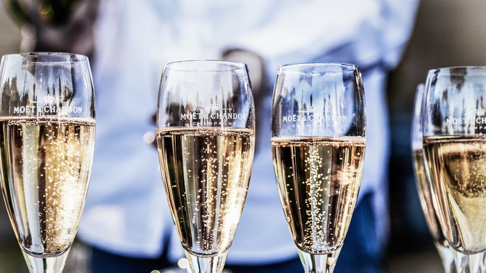 Vier Champagnergläser mit Getränk, Person im Hintergrund