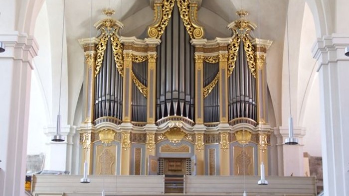 Prachtvolle Kirchenorgel mit goldenen Verzierungen in einem großen Kirchenraum