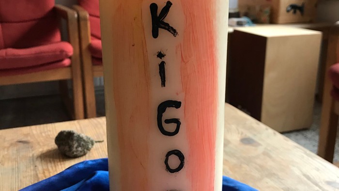 Kerze mit der Aufschrift "Kigodi" steht auf Tisch