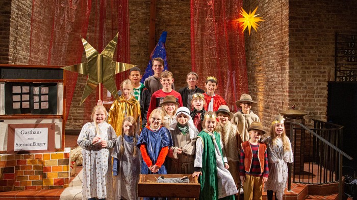 Kinder in bunten Kostümen posieren gemeinsam auf der Bühne.