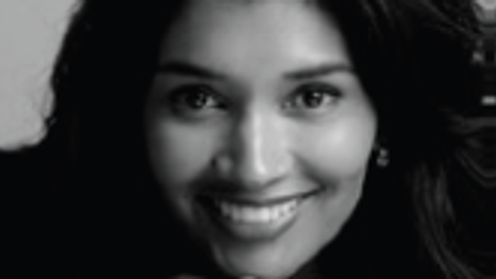 Kvinde med langt mørkt hår, der hviler hagen i hånden på et sort-hvidt portræt.