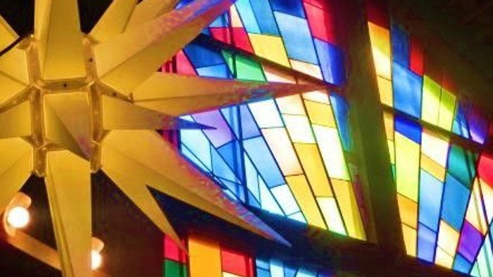 Leuchtende Papiersterne vor buntem Kirchenfenster