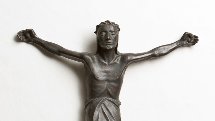 Eine Bronzestatue eines Mannes mit ausgebreiteten Armen an einer Wand