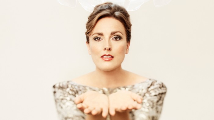 En kvinde med hår i en bun ser overrasket ud og har hænderne i en gest.