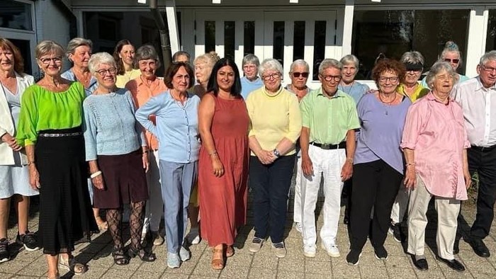 En gruppe pensionister står sammen udenfor et hus