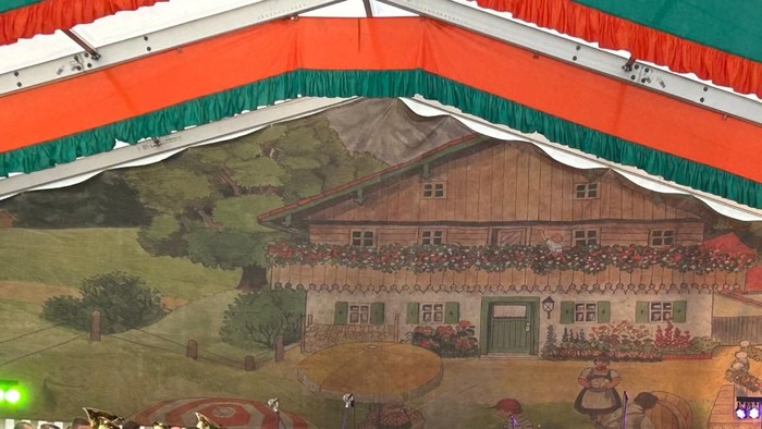 Ein lebendiges Wandgemälde eines Schweizer Chalets mit einem grün-orangen Baldachin.