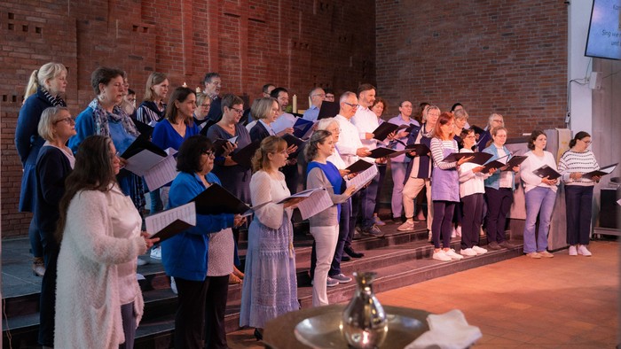 Ein Chor singt in einem Raum mit Backsteinwänden