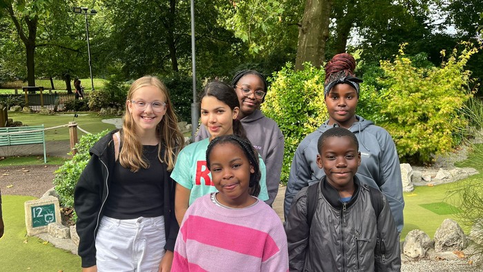 Group of six children posing outdoors, smiling for the camera.