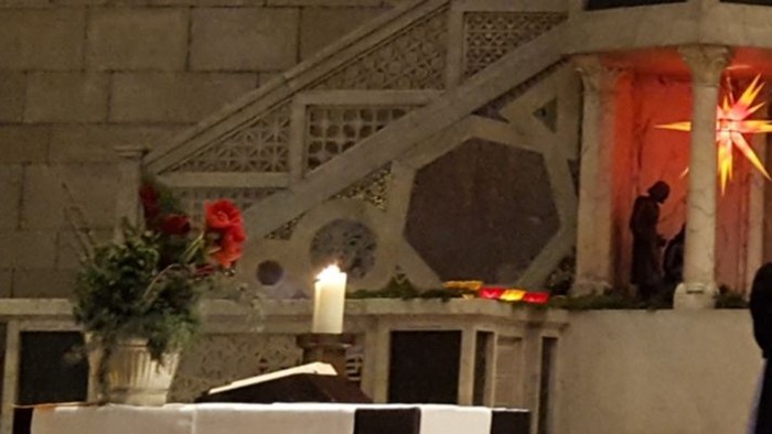 Eine Gruppe von Menschen singt in einem großen Raum, begleitet von einem Pianisten.