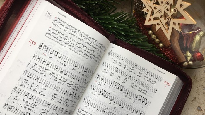 Aufgeschlagenes Gotteslob neben Tannenzweigen und Weihnachtsstern aus Holz