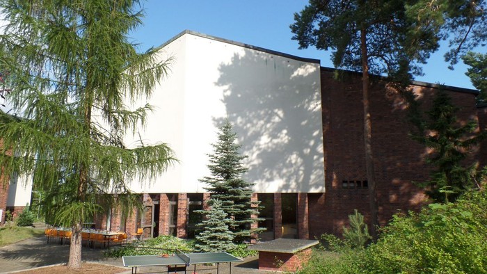 Das Bild zeigt ein Gebäude mit einem Innenhof, einem Tischtennisplatte und Bäumen.