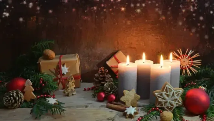 En juledekoreret bord med lysende lysekøn, gavekasser, og pynt.